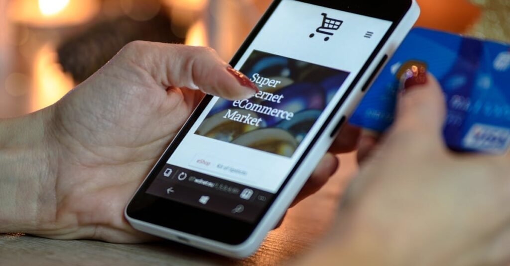 Woman using smartphone for online shopping with credit card in hand, festive background lighting.