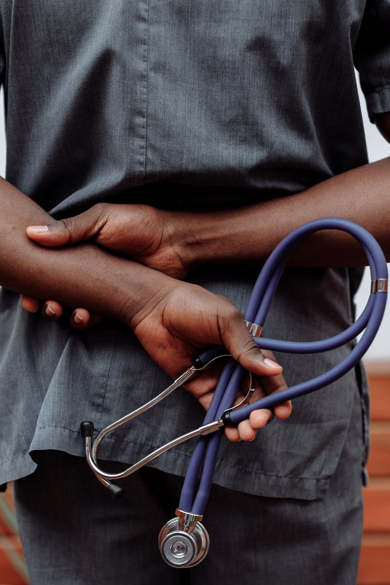 pexels-photo-5327647-5327647 Medical professional in gray scrubs holding stethoscope behind back.