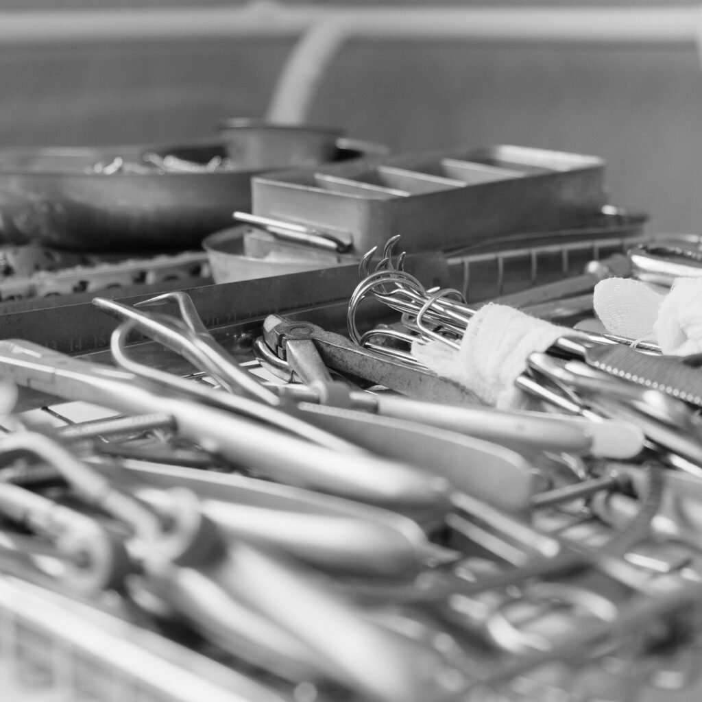 Close-up of sterile surgical instruments arranged on a tray, captured in black and white.